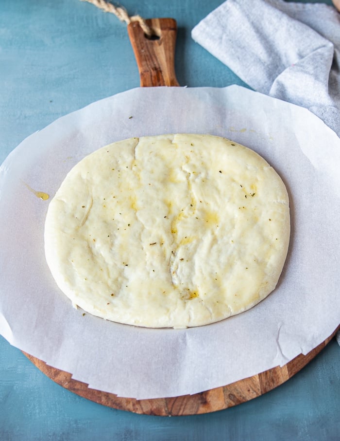 raw pizza dough on a piece of papers stretched and ready to use