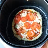 toppings added onto the pizza dough in the air fryer basket to continue air frying