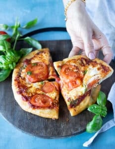 A hand holding a slice of perfectly cooked air fryer pizza