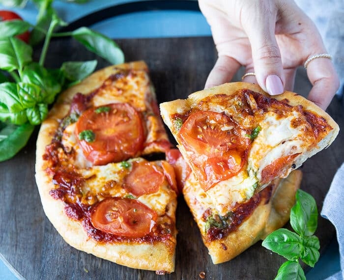 A hand holding a slice of perfectly cooked air fryer pizza