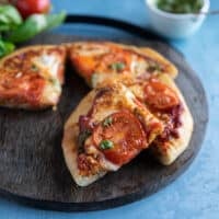 air fryer pizza sliced up on a cutting board with a slice overlapping to show the texture