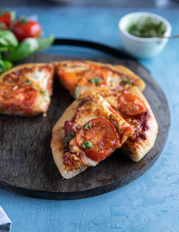 air fryer pizza sliced up on a cutting board with a slice overlapping to show the texture