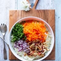 All fish taco slaw recipe ingredients in a large bowl added together: cabbage, carrots, cilantro, onions, apples