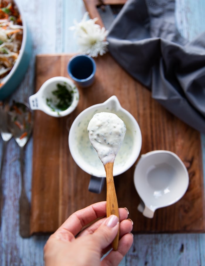 the coleslaw dressing mixed together in a bowl and a spoon showing the final dressing