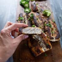 A hand holding a cooked piece of mahi mahi fish to show how thick and firm the texture is