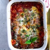 close up of veal parmesan baked in tomatoe sauce and topped with parmesan cheese, mozzarella and fresh basil