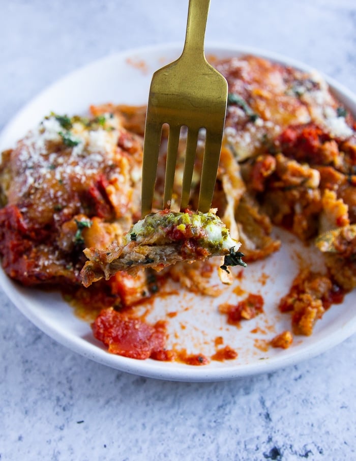 veal parmesan served on a plate and cut up. a fork holding off the pieces of veal parmesan to show the texture