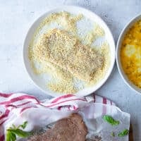 the veal cutlet added to the breadcrumbs plate for breading and final coat