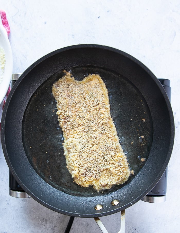 pan searing the breaded veal cutlet in a hot pan with oil