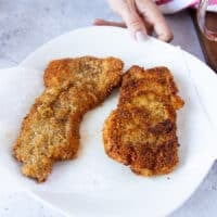 crispy golden brown veal cutlets drying on a paper towel