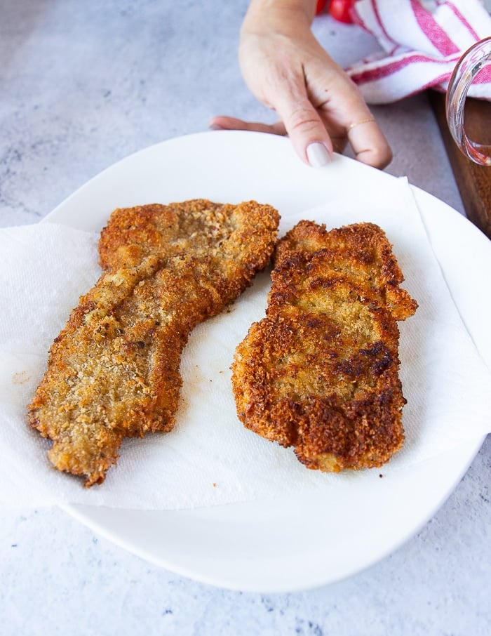 crispy golden brown veal cutlets drying on a paper towel