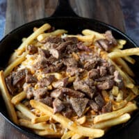cut up chunks of meat is added over the cheese on the fries to make carne asada fries recipe