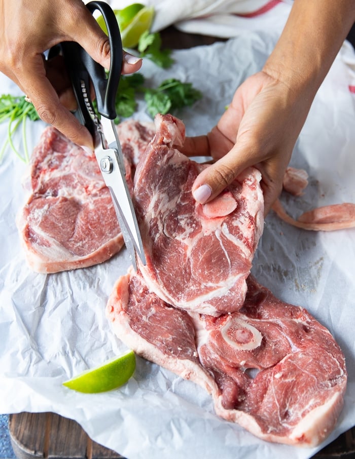 Una mano con le forbici per tagliare il grasso in eccesso dalla carne prima dell'uso