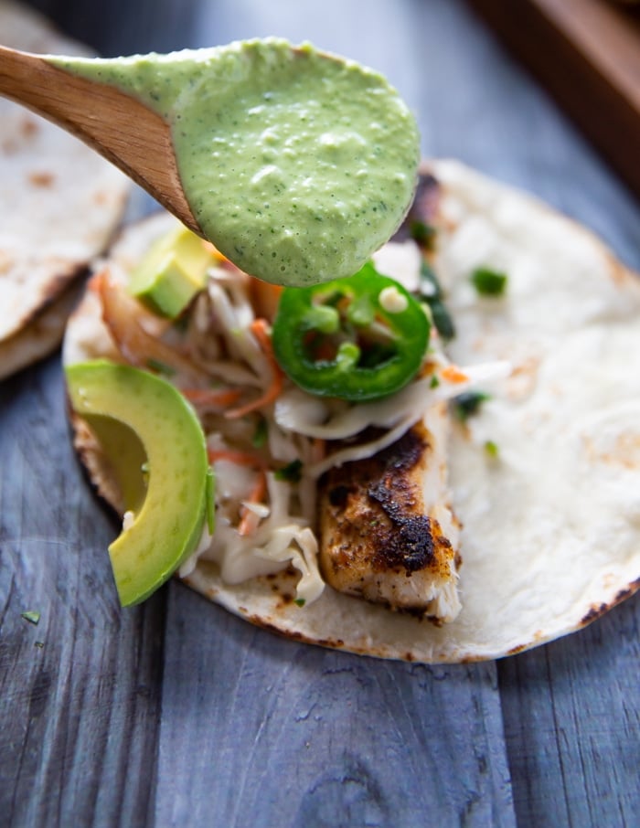 A final drizzle of poblano sauce over the fish tacos to finish it off