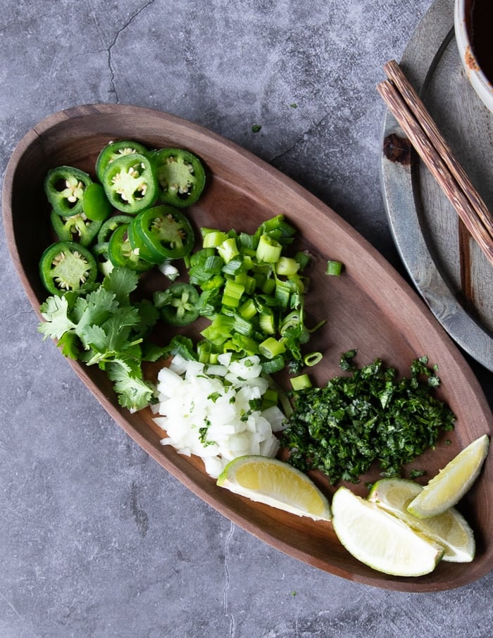 toppings for the birria ramen which include diced onions, sliced jalapenos, chopped cilantro and lime wedges