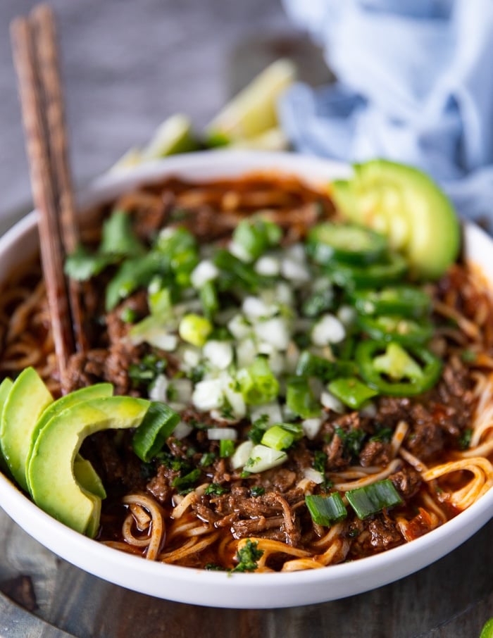 close up of a finished bowl of birria ramen showing the birria stew and the birria meat drenching cooked noodles with the toppings