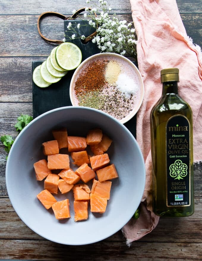 Ingredients for the salmon tacos including salmon cut up into chunks, olive oil, spice blend, lime