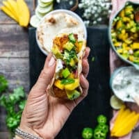 A hand holding a finished salmon taco showing the cooked salmon and salsa