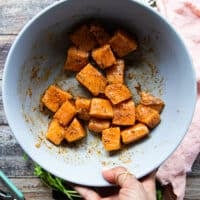 Salmon chunks coated in spice and olive oil in a large bowl and ready to cook for salmon tacos