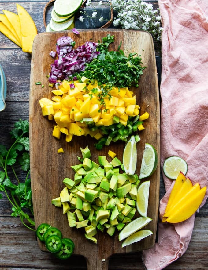 ingredients for avocado salsa including cilantro, onions, lime, manho chunks and avocado chunks