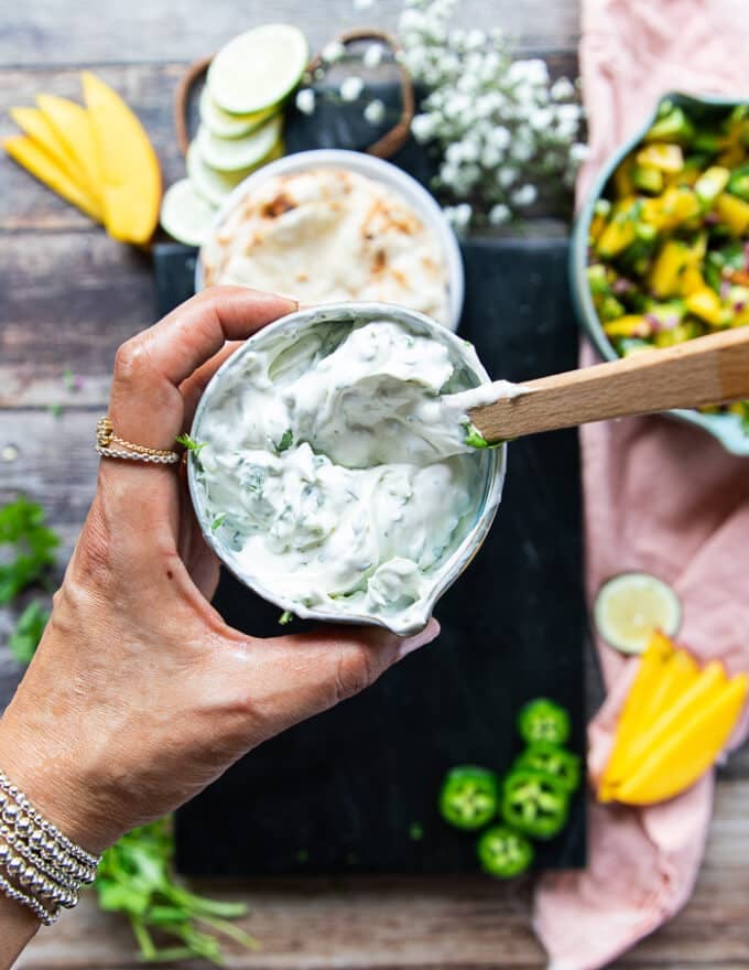 a hand holding a bowl of sour cream ready with herbs