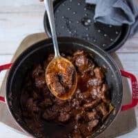 A spoon showing the4 cooked tender lamb chunks in the lamb stew