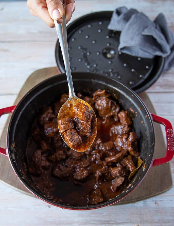 A spoon showing the4 cooked tender lamb chunks in the lamb stew