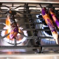 The eggplants placed directly over the flame of a stove (or BBQ)