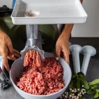 The meat is grinding in a grinder and into a large bowl