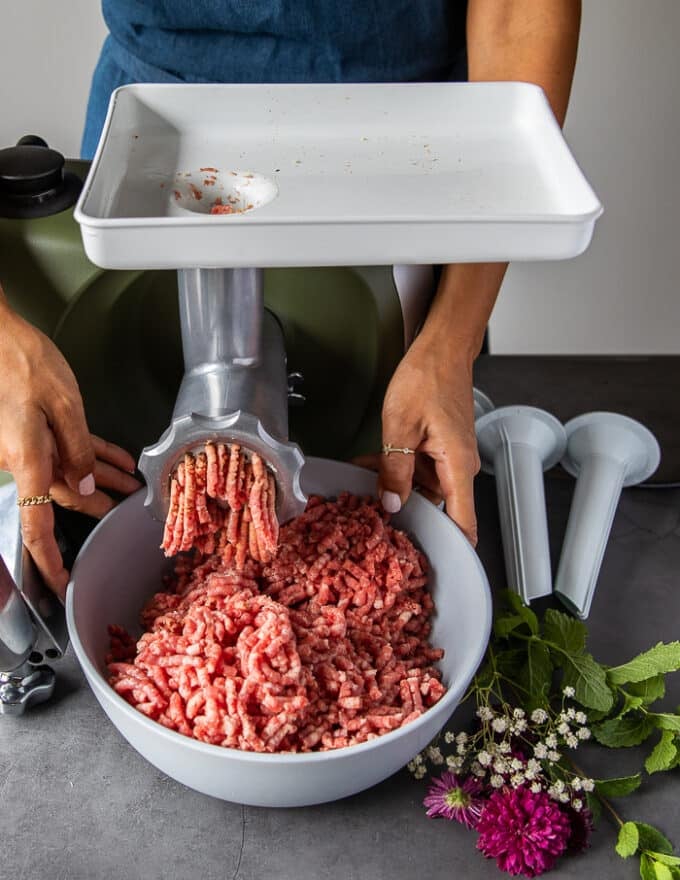 The meat is grinding in a grinder and into a large bowl