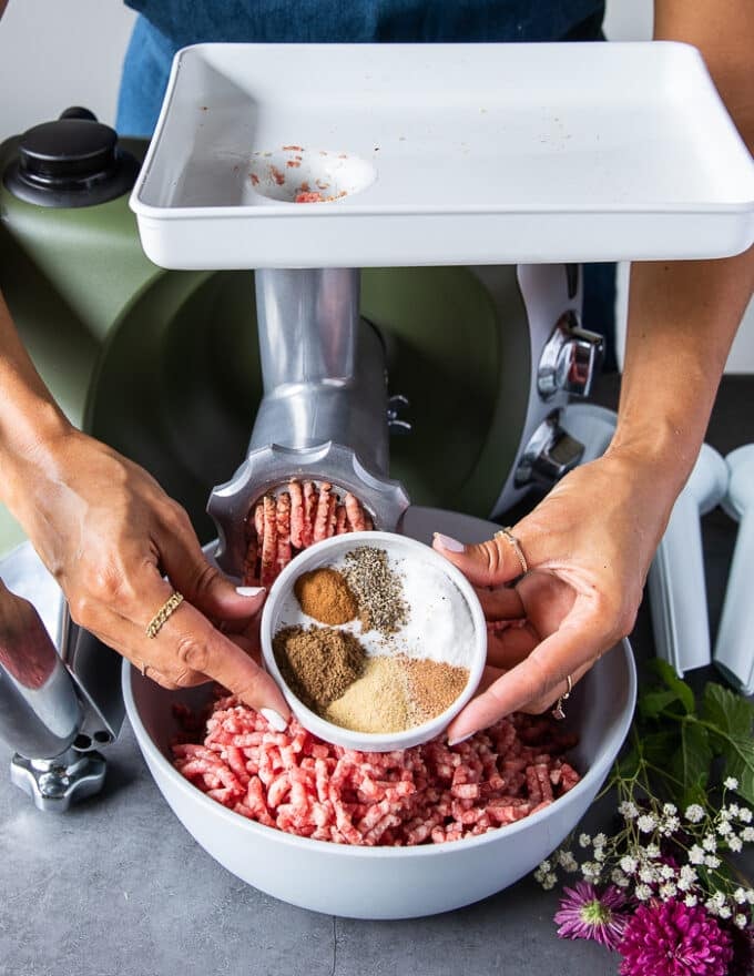 A hand holding the spice blend used to make the sausage