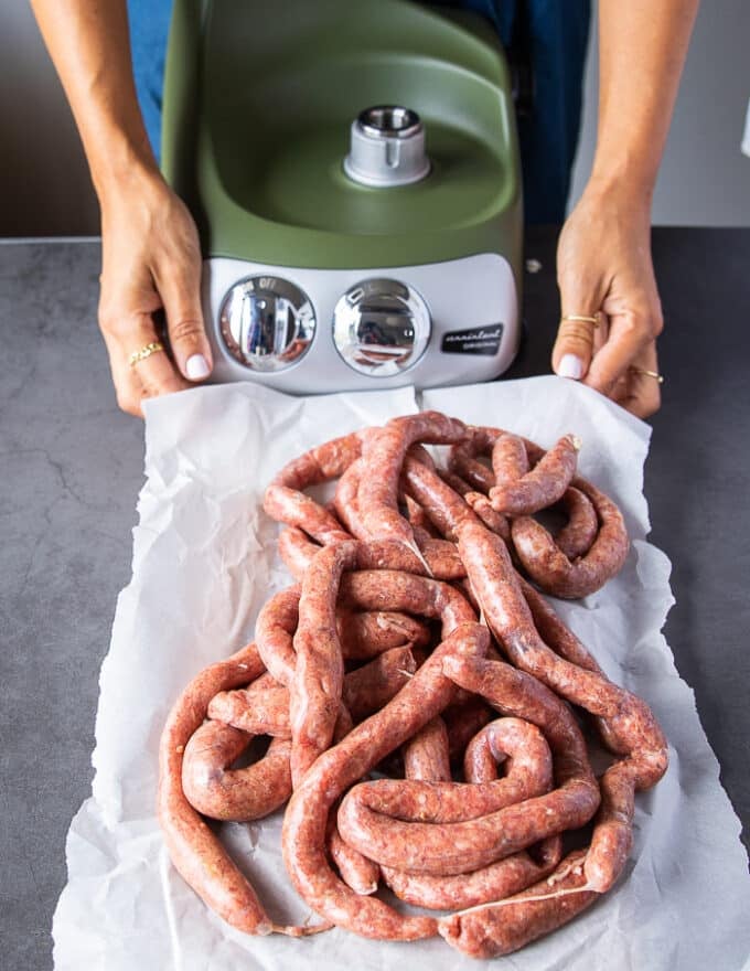 A hand holding a tray of all the sausage links ready and out of the machine