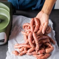 A hand tying up the finished sausage to make sausage links