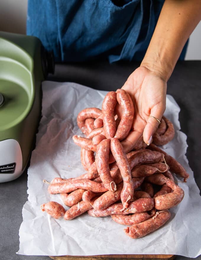 A hand tying up the finished sausage to make sausage links