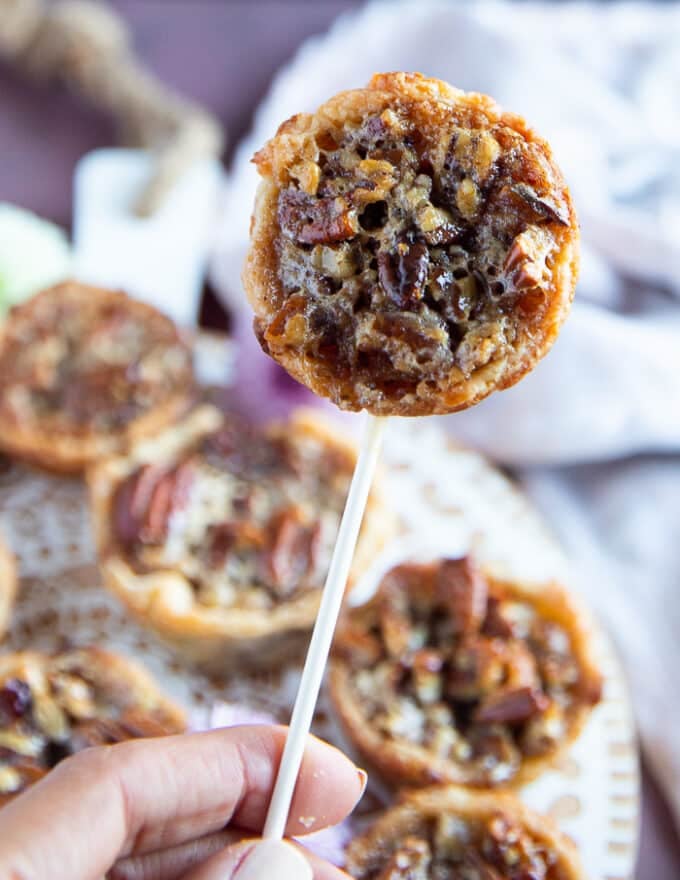 A hand holding a pecan pie in a lollipop stick