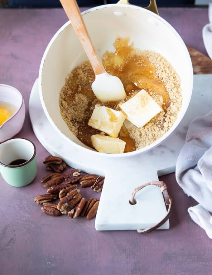 A pot with the sugar and honey cooking until just melted into one mixture and butter being added