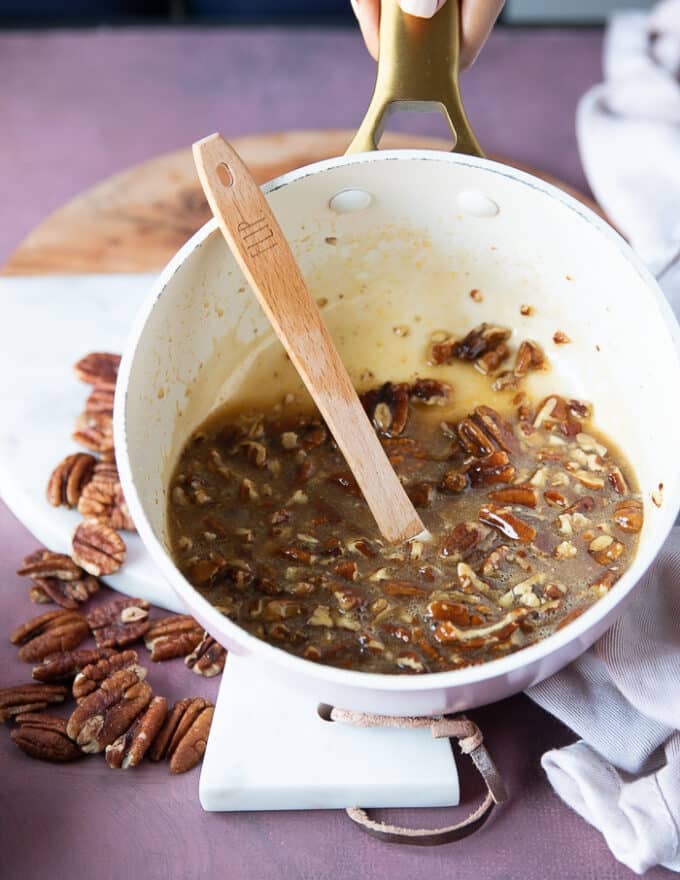 Pecans being added to the butter and egg mixture in the post and mixed in