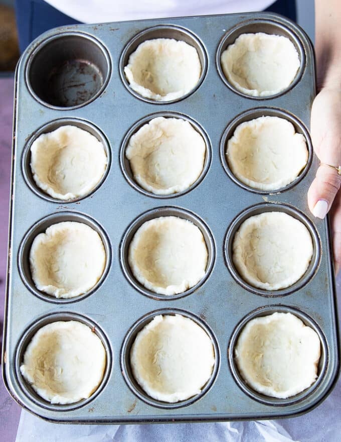 The pie dough is divided among the 12 cavities of the muffin pan and ready to bake. 