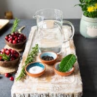 brine ingredients for turkey tenderloin recipe including water, a small bowl of salt, small bowl of sugar, whole bay leaves and whole peppercorns