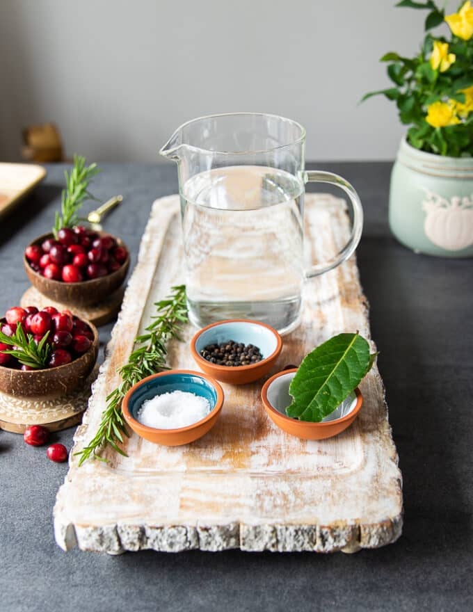 brine ingredients for turkey tenderloin recipe including water, a small bowl of salt, small bowl of sugar, whole bay leaves and whole peppercorns