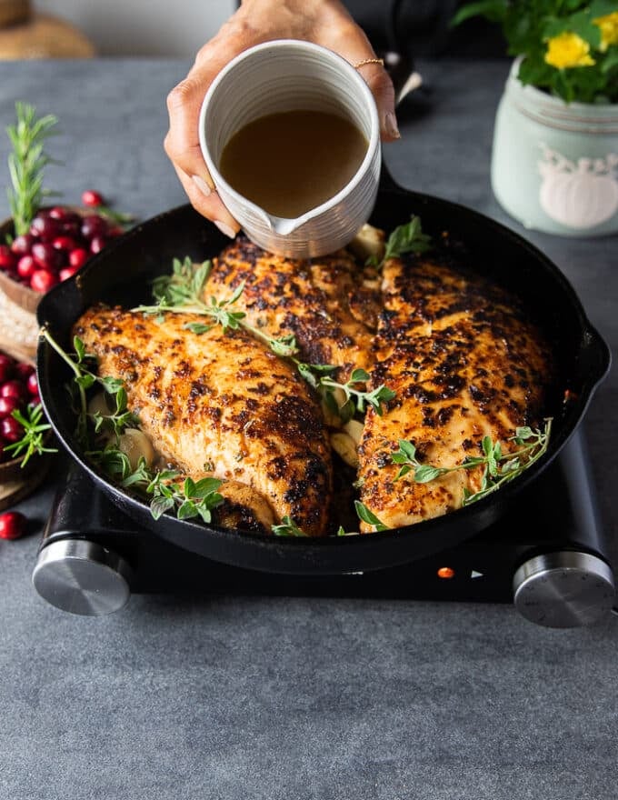 A hand pouring the stock over the turkey tenderloin recipe