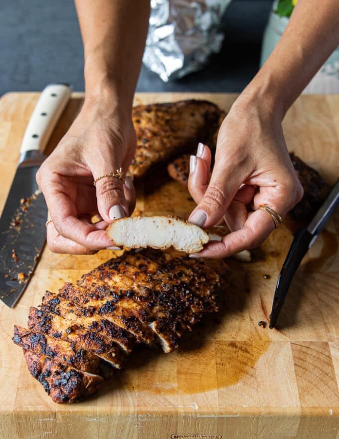 A hand holding a piece of turkey tenderloin just sliced and showing how juicy it is out of the oven