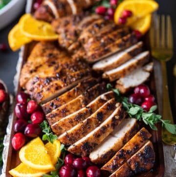 close up of one turkey tenderloin recipe sliced up and served with orange slices around