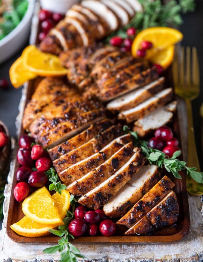close up of one turkey tenderloin recipe sliced up and served with orange slices around