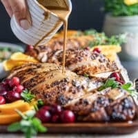A hand pouring the gravy over the sliced turkey tenderloin recipe