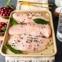 Turkey tenderloins in a deep plate with the brine added and some whole pepper corns