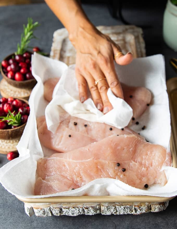 A hand patting dry the turkey tenderloin after brining