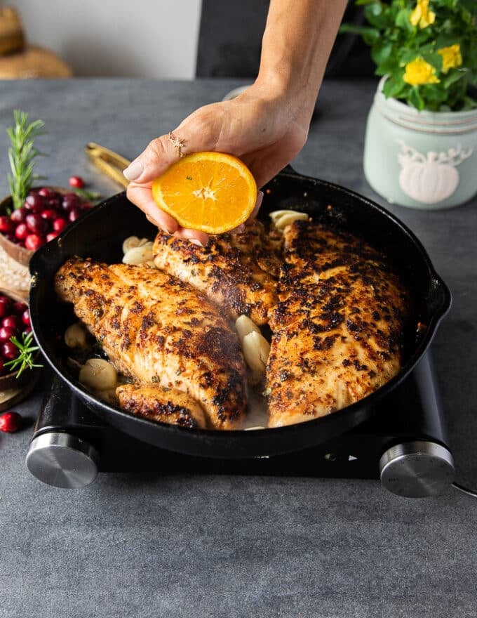 A hand squeezing orange juice over the tukey