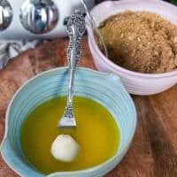The ball of monkey bread dough is dipped into a bowl of melted butter