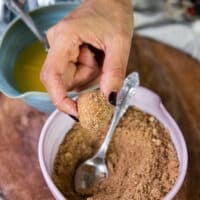 The dough is now dipped into a bowl of cinnamon sugar and coated well using a spoon